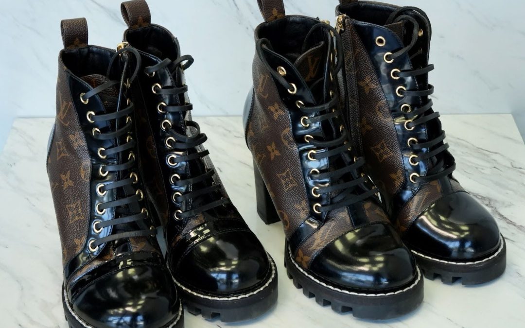 Pair of Louis Vuitton ankle boots with glossy black toes and brown monogram leather, restored to a polished finish on a marble surface.